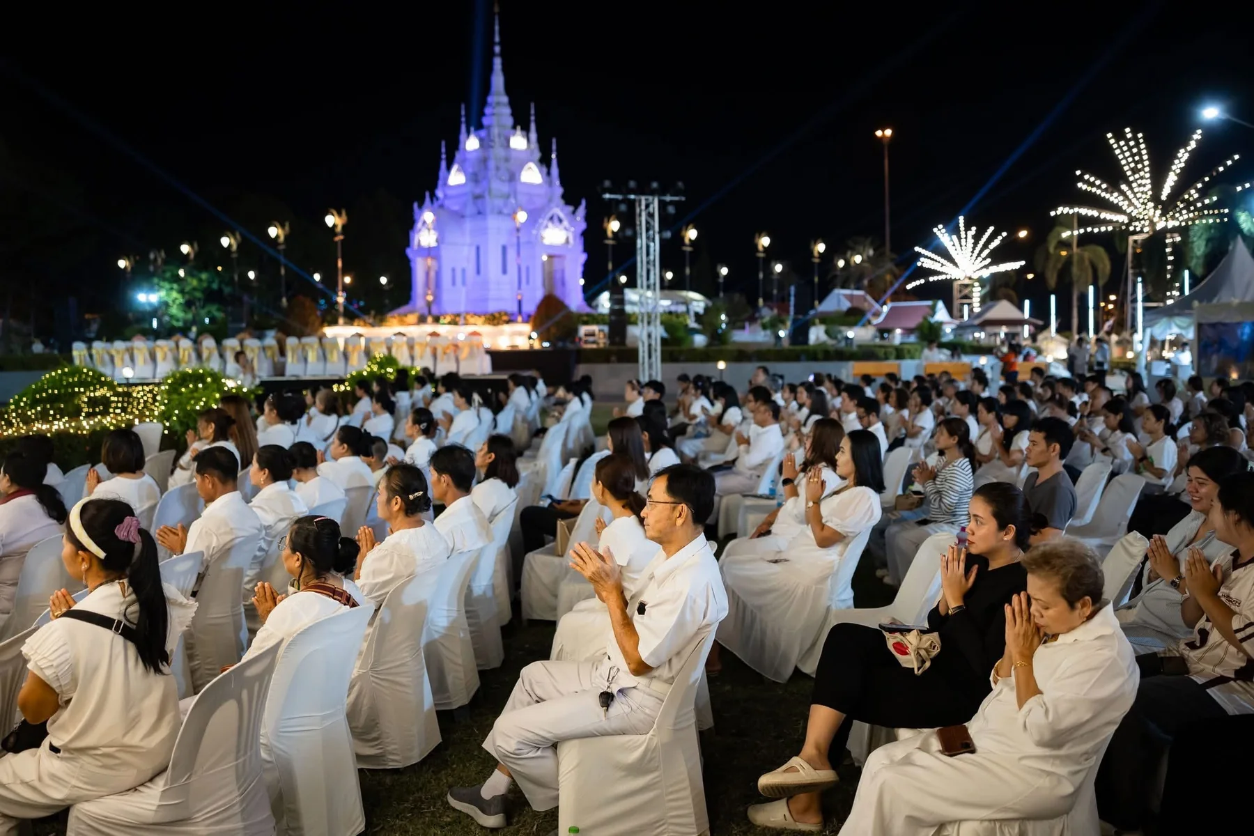 ผู้ร่วมงานประกอบพิธีท่ามกลางแสงไฟยามค่ำคืน