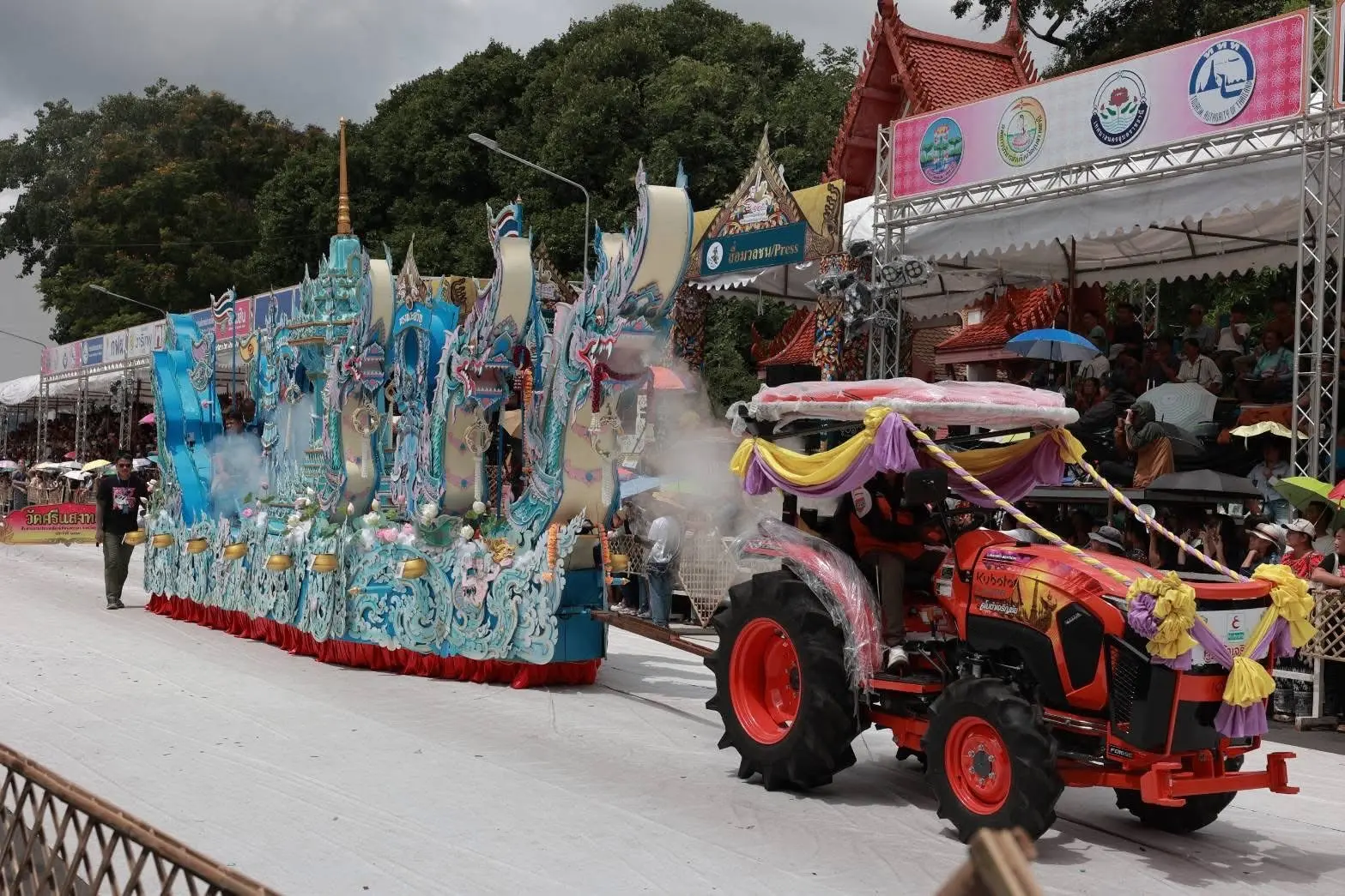 ขบวนเรือเทียนประดับลวดลายสีฟ้าเคลื่อนผ่านผู้ชม